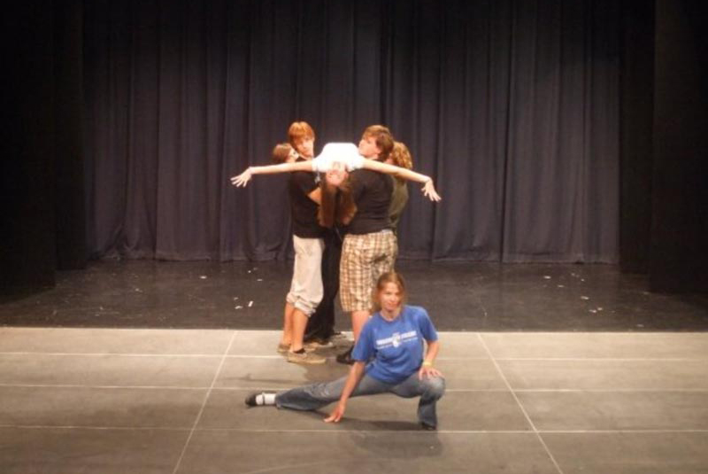 Stage performers hold a woman upsidedown while she sings.